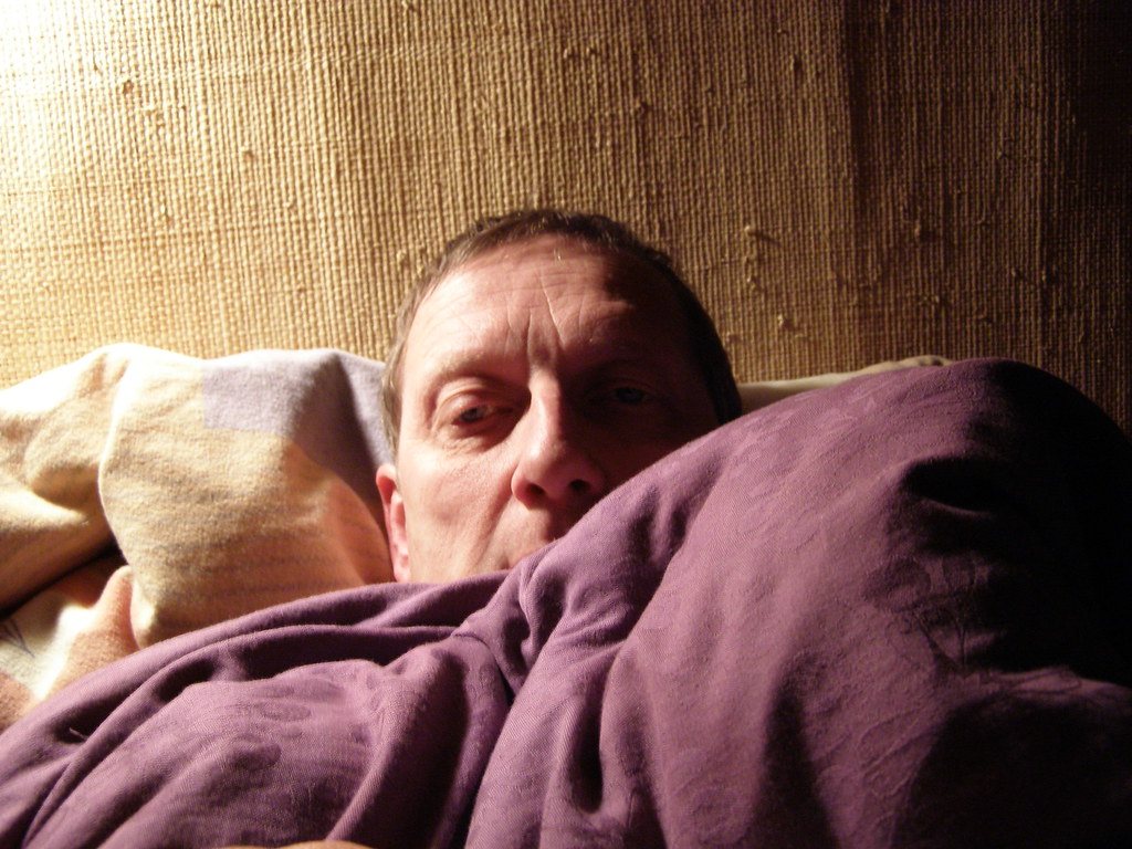 Man lying in bed looking unwell